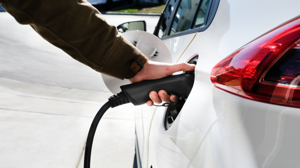 Person's hand attaching an EV charger to a white EV.